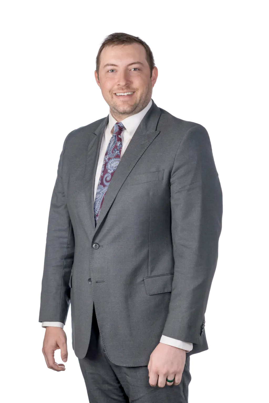A man in a gray suit and patterned tie stands and smiles against a plain white background.