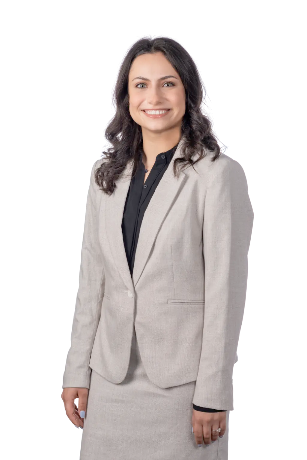 A woman in a light beige suit and black blouse smiles while standing against a plain background.