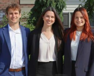 Three young adults stand outside of office in business attire